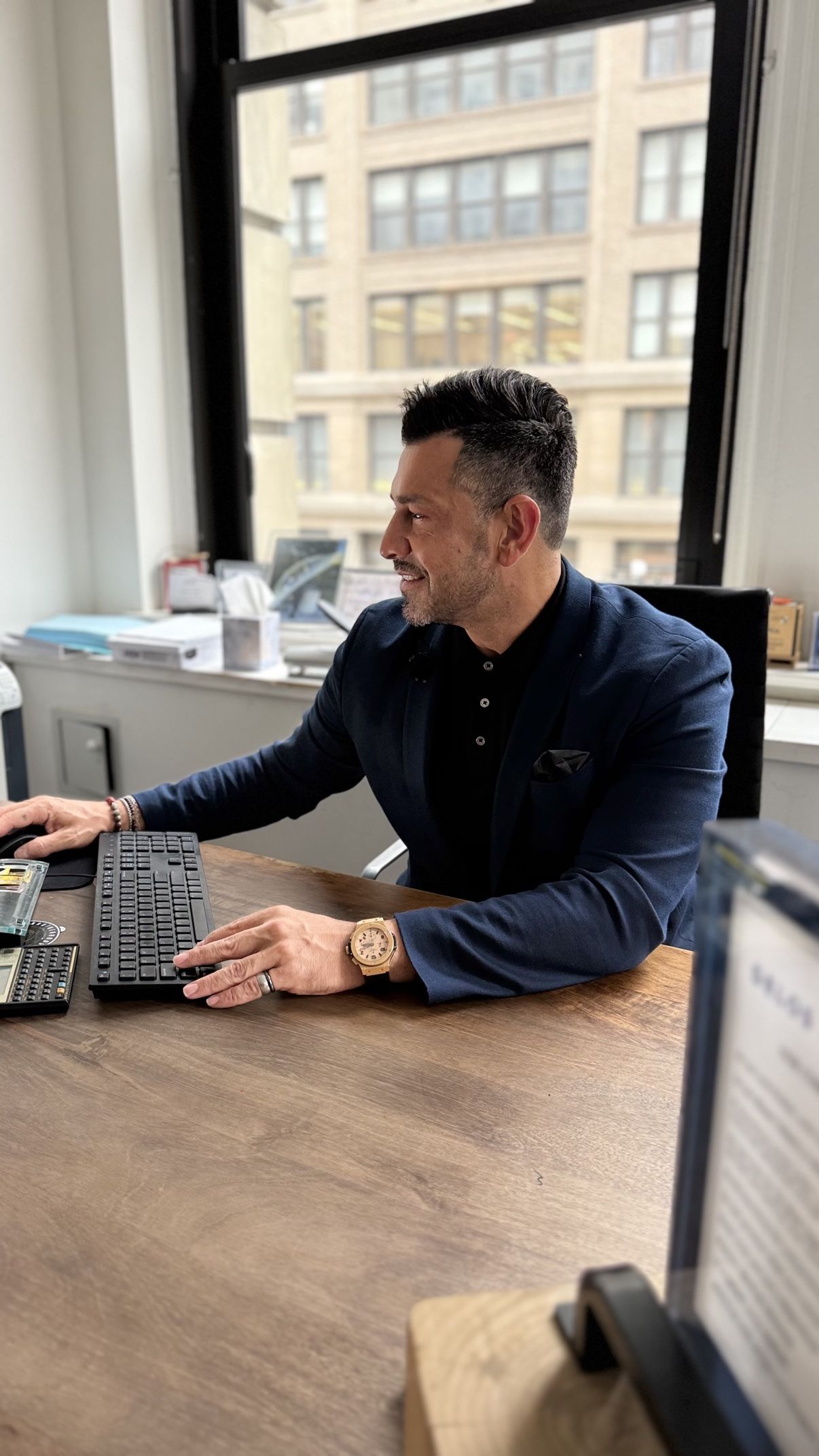 Richie Hosein working at his office desk in a navy jacket